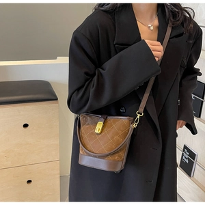 Detail of vintage brown bucket bag with quilted patterns and gold metal lock on a model