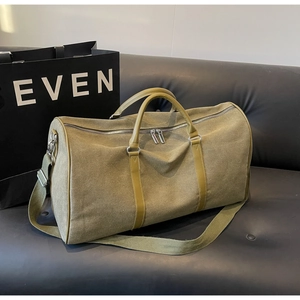 Detail of olive green canvas travel bag showing silver zippers and sturdy leather handles
