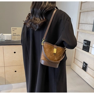 Detail of a brown quilted bucket bag featuring a gold twist-lock and contrast stitching