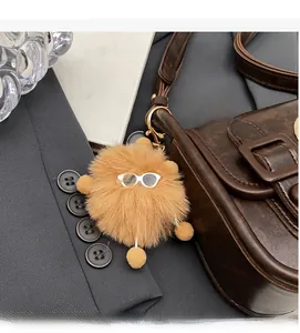 Détail d'un bijou de sac pompon marron avec lunettes et fermoir mousqueton doré