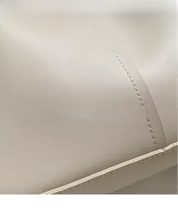 Detailopname van beige leer met lychee-textuur en fijn stiksel op de tote bag