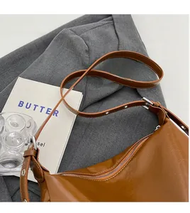 Detail of adjustable long shoulder strap with silver buckle on brown oil-wax leather bag