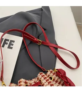 Gros plan sur un sac en tweed rouge et blanc avec bandoulière et boucles dorées