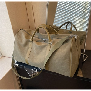 Close-up of olive green canvas travel bag with leather handles and silver hardware