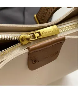 Detail van de gouden rits met merkgravure op de gebroken witte lederen bucket bag