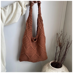 Primo piano della borsa tote in maglia caramello con trama a trecce e motivo a rombi