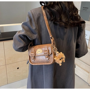 Petit sac carré vintage marron avec patch chiot et peluche porté à l'épaule par un mannequin