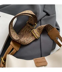 Detail van beige emmertas met vintage bruine brede geweven riem op grijs pak
