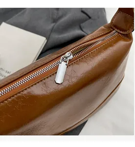 Close-up of smooth silver metal zipper and vintage wrinkled leather on caramel shoulder bag