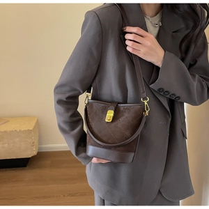 Detail view of dark brown bucket bag featuring quilted texture and golden hardware buckle