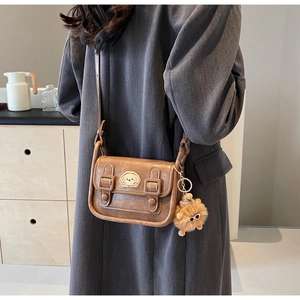 Détail d'un sac bandoulière vintage marron avec patch chiot et breloque lion en peluche
