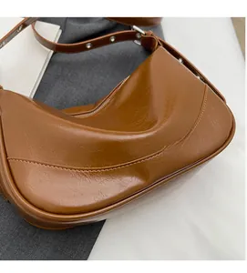 Close-up of vintage brown oil wax leather hobo bag with adjustable strap and curved stitching