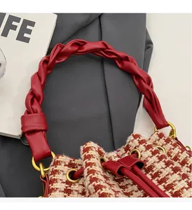Détail du sac à carreaux rouges et blancs avec poignée en cuir tressé et anneaux dorés