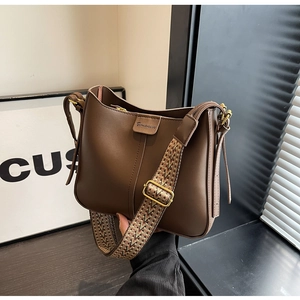 Close-up of coffee brown leather tote with a textured woven shoulder strap and gold hardware