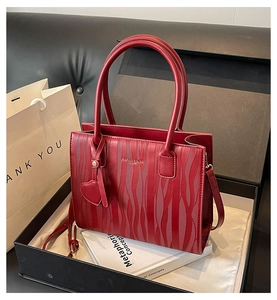 Détail du sac cabas rouge avec texture ondulée, pendentif coeur et bandoulière réglable