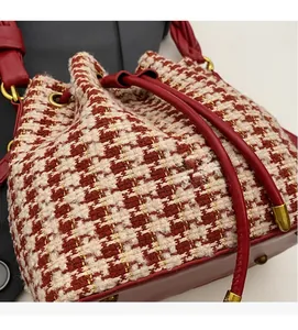 Détail du sac seau en tweed pied-de-poule rouge et blanc avec cordon en cuir et dorures
