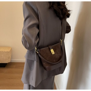 Detail of a dark brown bucket bag showing quilted texture and golden metallic lock