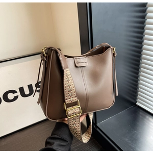 Detail view of dark brown bucket bag with geometric patterned wide strap and matte leather