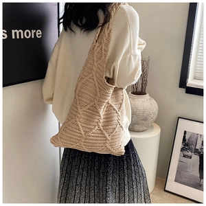 Dettaglio della borsa tote in maglia beige con motivo a uncinetto a rombi e trama morbida