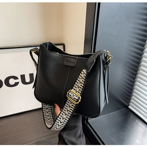 Detail of black leather shoulder bag featuring a geometric patterned wide textile strap