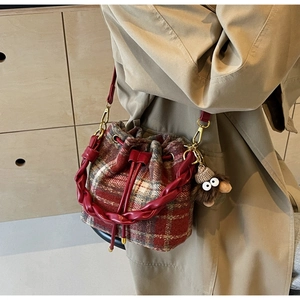 Détail du sac seau à carreaux rouges avec cordon, bandoulière et breloque peluche