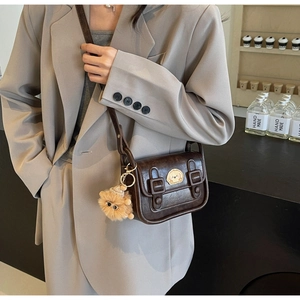 Gros plan du sac bandoulière marron rétro avec patch chiot et breloque peluche
