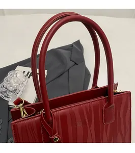 Détail du sac à main de mariée rouge avec texture ondulée et accents métalliques dorés