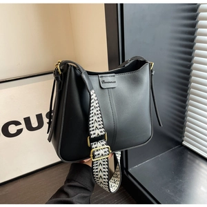 Detail of minimalist black leather bucket bag featuring a modern woven geometric strap
