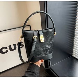 Detail view of black bucket bag with quilted suede texture and leather base