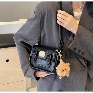 Détails d'un sac à bandoulière rétro noir en similicuir avec double sangle et breloque peluche
