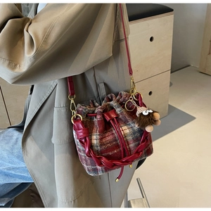 Détail du sac seau en laine à carreaux avec anse tressée rouge et charm monstre poilu