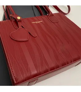 Détail du sac à main de mariage rouge foncé avec texture ondulée et logo doré