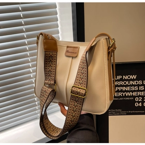 Detail of cream PU leather bucket bag with wide geometric patterned canvas strap