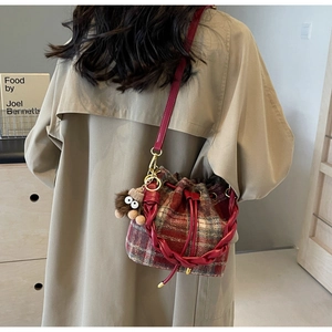 Détail du sac seau en tweed à carreaux rouge et blanc avec breloque peluche et cordon serrage