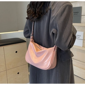 Close-up of pink shiny patent leather hobo bag with adjustable strap and silver buckle