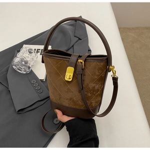 Detail of dark brown bucket bag with quilted stitching and gold metallic twist lock