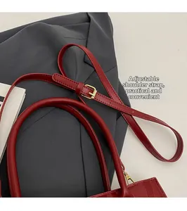 Vue détaillée du sac de mariage rouge avec bandoulière réglable et boucle dorée