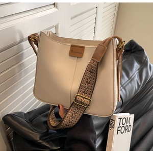 Detail of cream leather bucket bag with retro embroidered strap and logo plaque