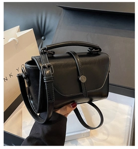 Detail view of the black crossbody bag showing its fine leather texture and metal buckle