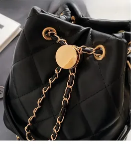 Close-up of quilted bucket bag with gold hardware, drawstring and leather chain strap