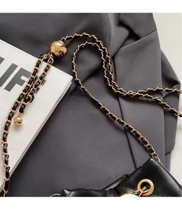 Detail of black quilted leather bucket bag with gold chain and spherical metal adjuster