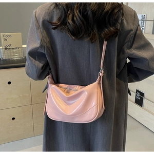 Detailed back view of pink glossy PU leather crescent bag worn with a grey blazer