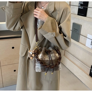Détail du sac seau en peluche à carreaux avec fermeture à cordon et breloque poupée