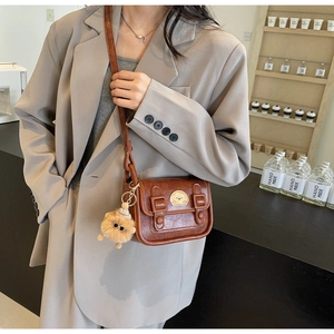 Petit sac rétro marron avec pendentif ours porté par un mannequin dans un café