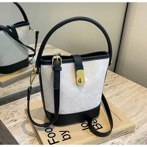 Detail of quilted bucket bag with contrast black and white design and golden hardware