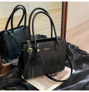 Détails du sac à main noir texturé à vagues avec finitions dorées et pendentif coeur