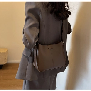 Detail of dark brown leather bucket bag with vertical stitching and wide shoulder strap