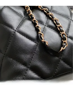Close-up of black quilted leather bucket bag with gold-tone metal woven chain strap