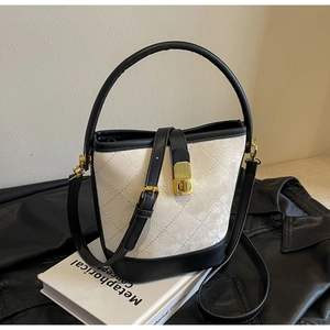Detail of quilted bucket bag with metal clasp, contrast stitching and round handle