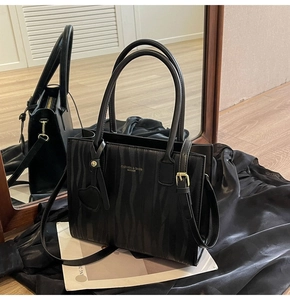 Détail du sac cabas noir avec texture zébrée, boucles dorées et logo de la marque